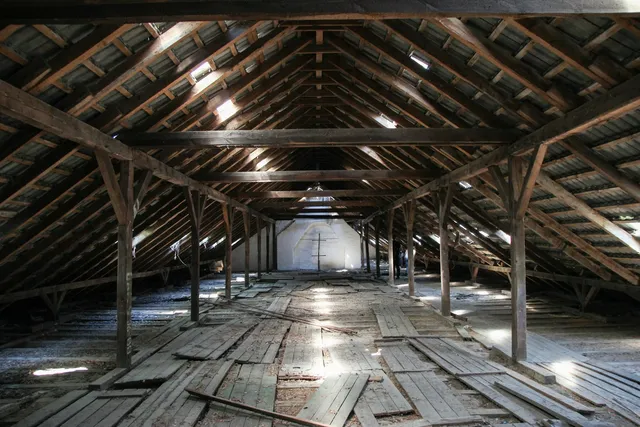 A long attic under a sloped roof, the beams low enough to touch from standing