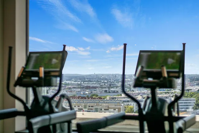 Two cardio machines standing unused in front of a window, the equipment a membership pays for whether or not anyone arrives