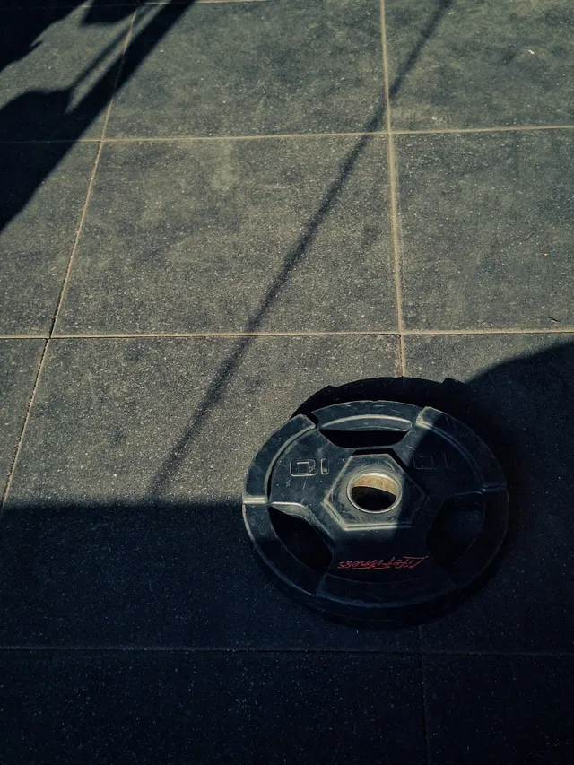 A single cast iron weight plate lying flat on a hard floor, seen from above