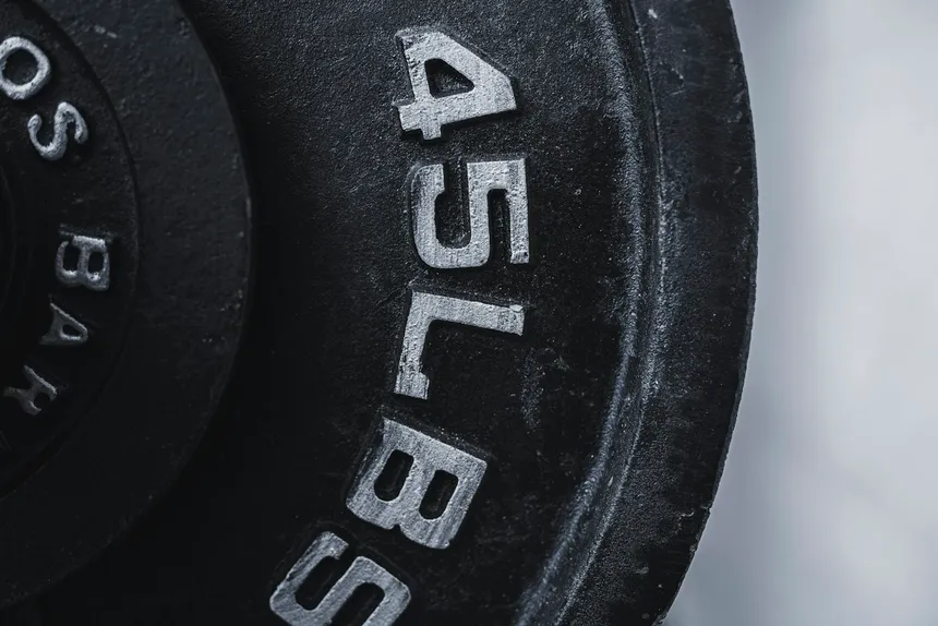 Close-up of a worn cast-iron 45 lb weight plate, the paint rubbed back to bare metal around the lettering
