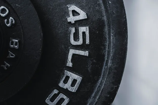 Close-up of a worn cast-iron 45 lb weight plate, the paint rubbed back to bare metal around the lettering