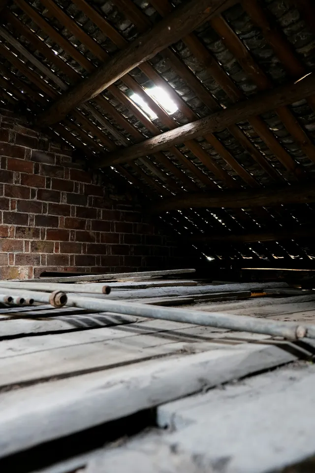 Bare floorboards in a loft with the roof slope coming down to meet a brick wall