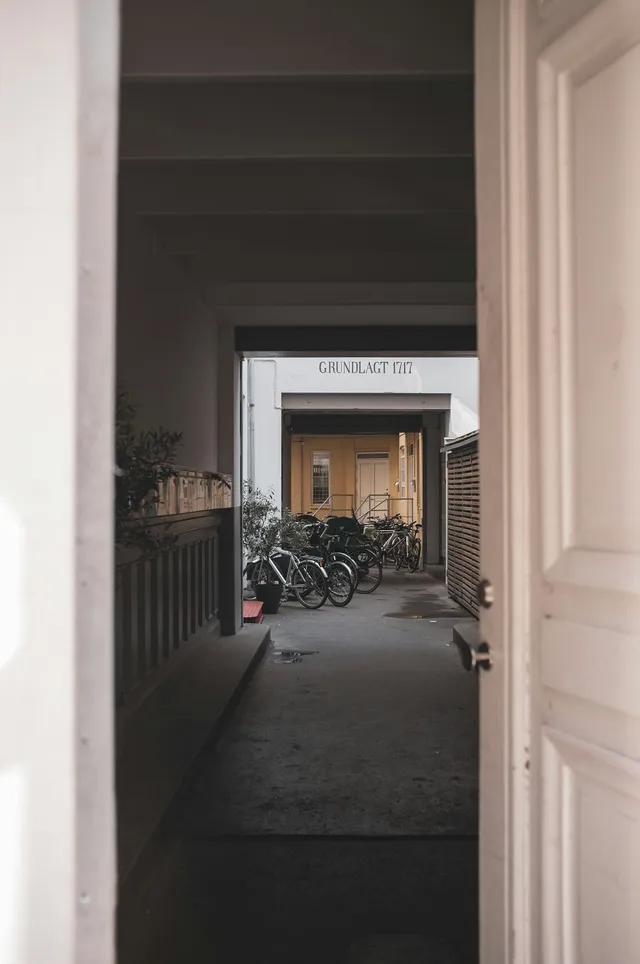 A doorway looking through to a dark hallway with bicycles parked along it
