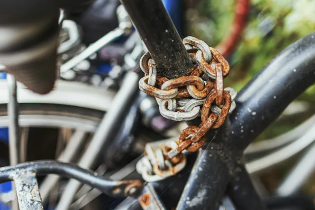 A heavy chain looped around a bicycle frame and a railing, showing how much length it takes to reach both