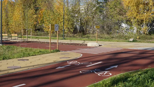 A red-surfaced cycle path curving away between trees, an ordinary mixed-conditions ride