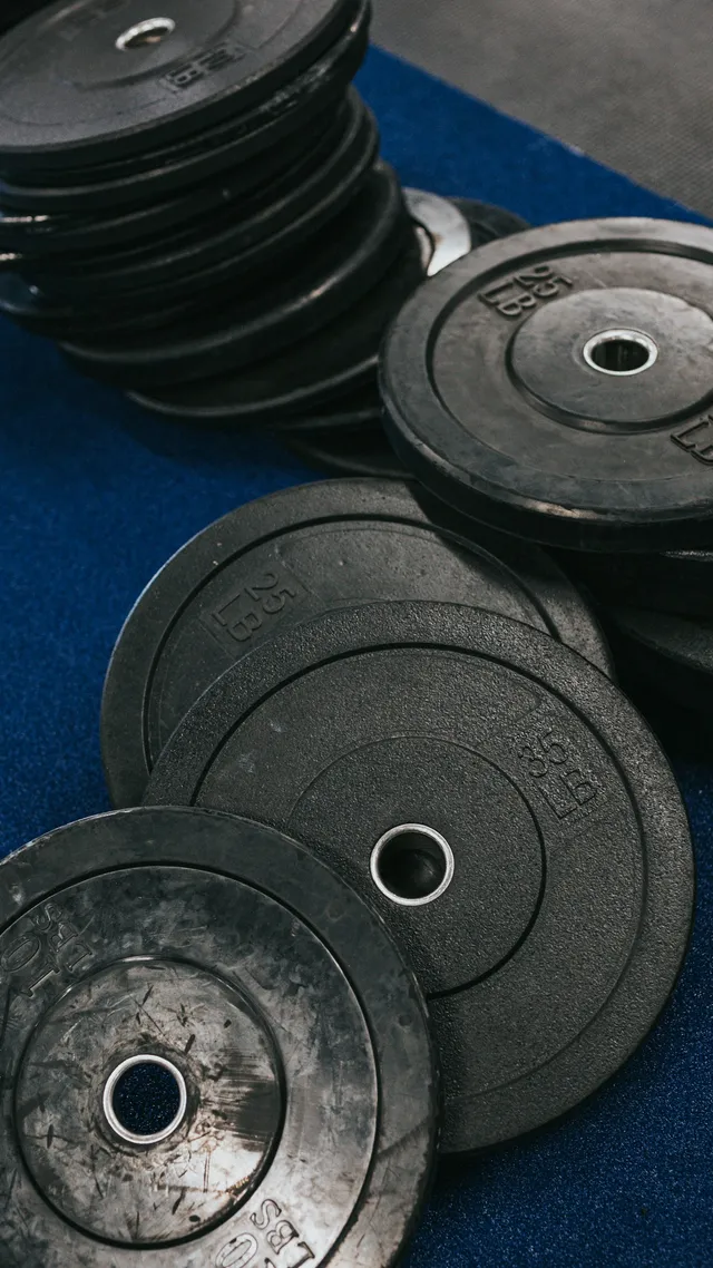 A stack of worn cast-iron weight plates resting on a blue gym mat, paint chipped back to metal