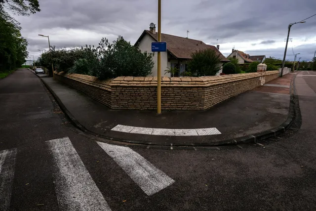 A residential street corner with a tight kerb radius and a visible camber falling away from the pavement