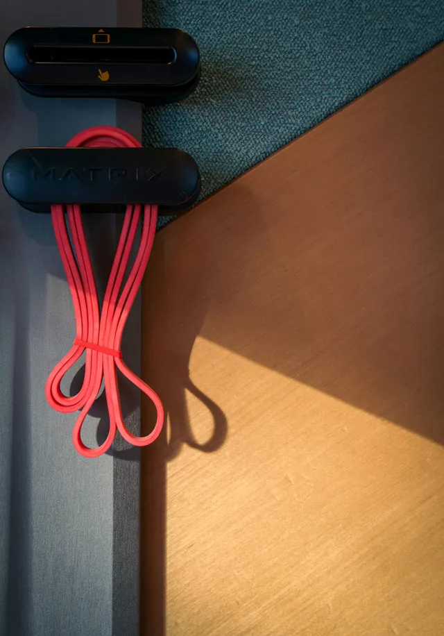 Resistance bands hanging from two small wall holders beside a doorway