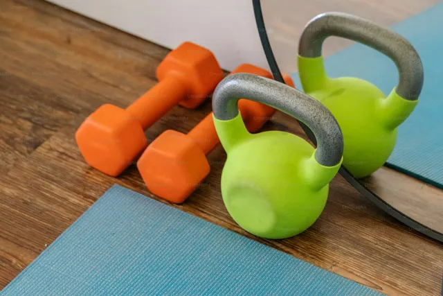 Kettlebells and dumbbells resting on an exercise mat, the kind of setup that needs nothing but floor