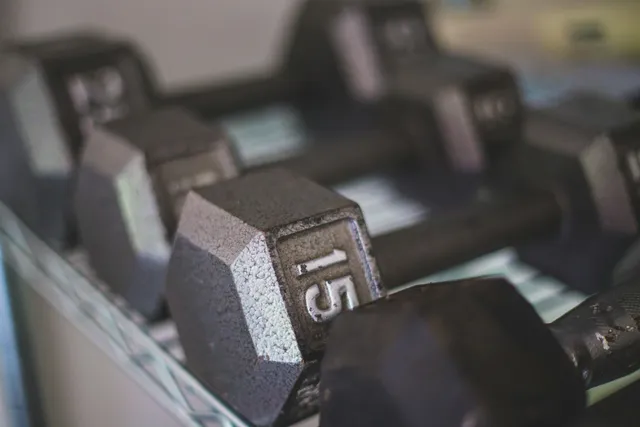 A close-up of a 15 lb hex dumbbell resting on a storage rack