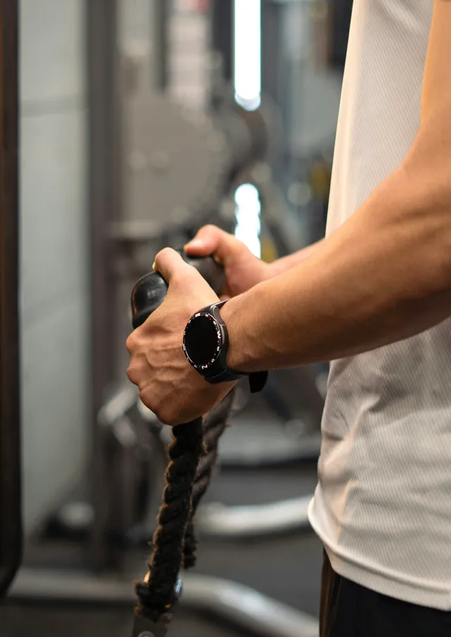Close-up of two hands gripping the rope handle of a cable machine under load