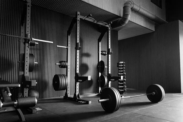 A power rack with a loaded barbell racked at chest height, plates stored on the uprights beside it